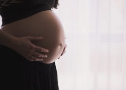 Side image of a pregnant women holding her stomach