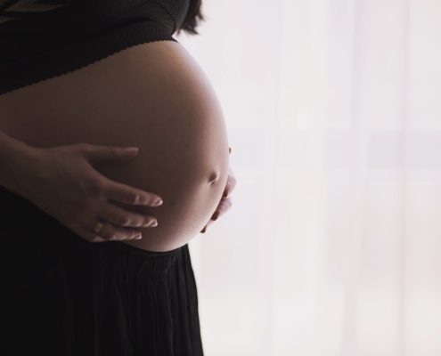 Side image of a pregnant women holding her stomach