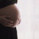 Side image of a pregnant women holding her stomach