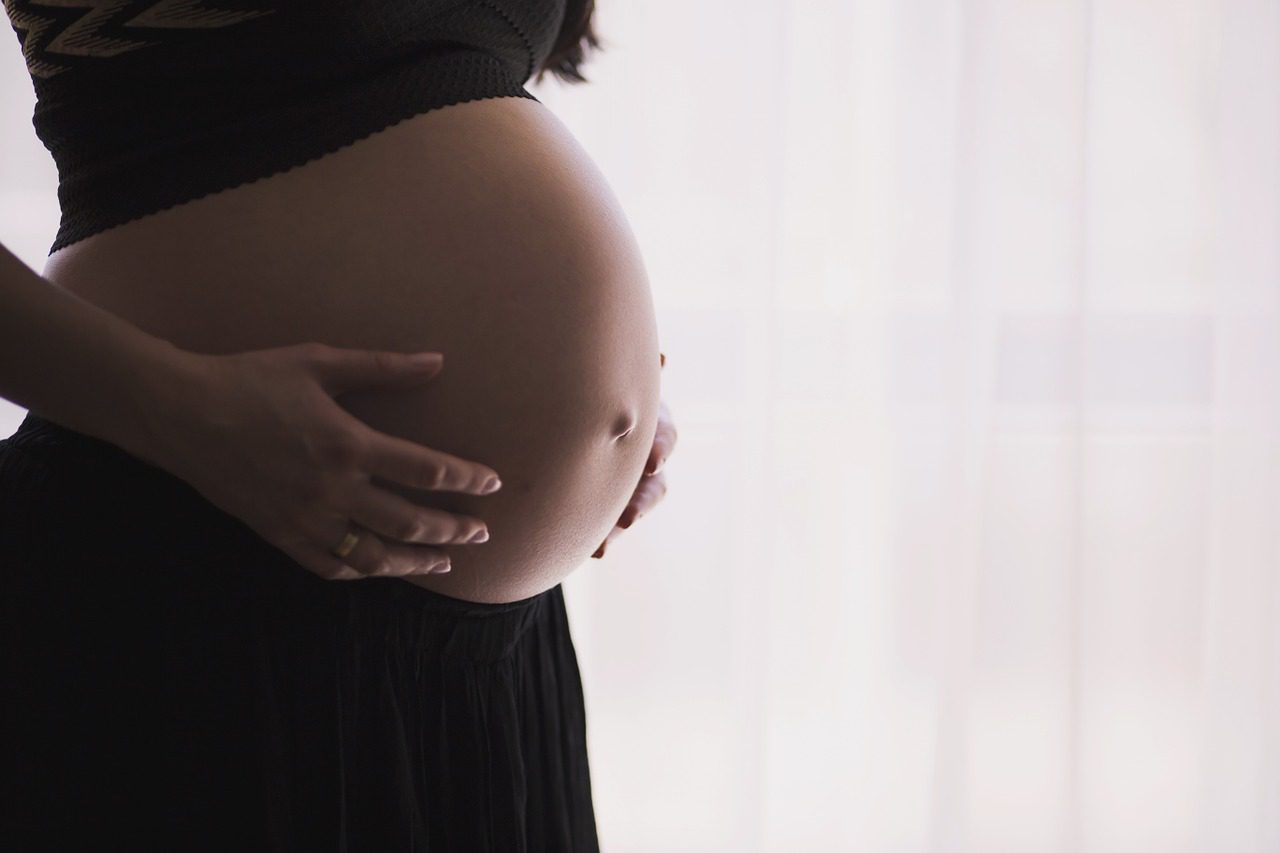 Side image of a pregnant women holding her stomach