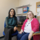 Two women sitting in front of a computer smiling