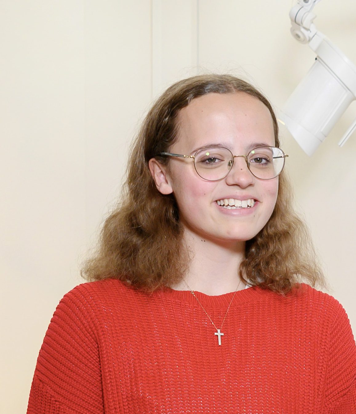 woman in a red jumper with glasses looking at the camera smiling
