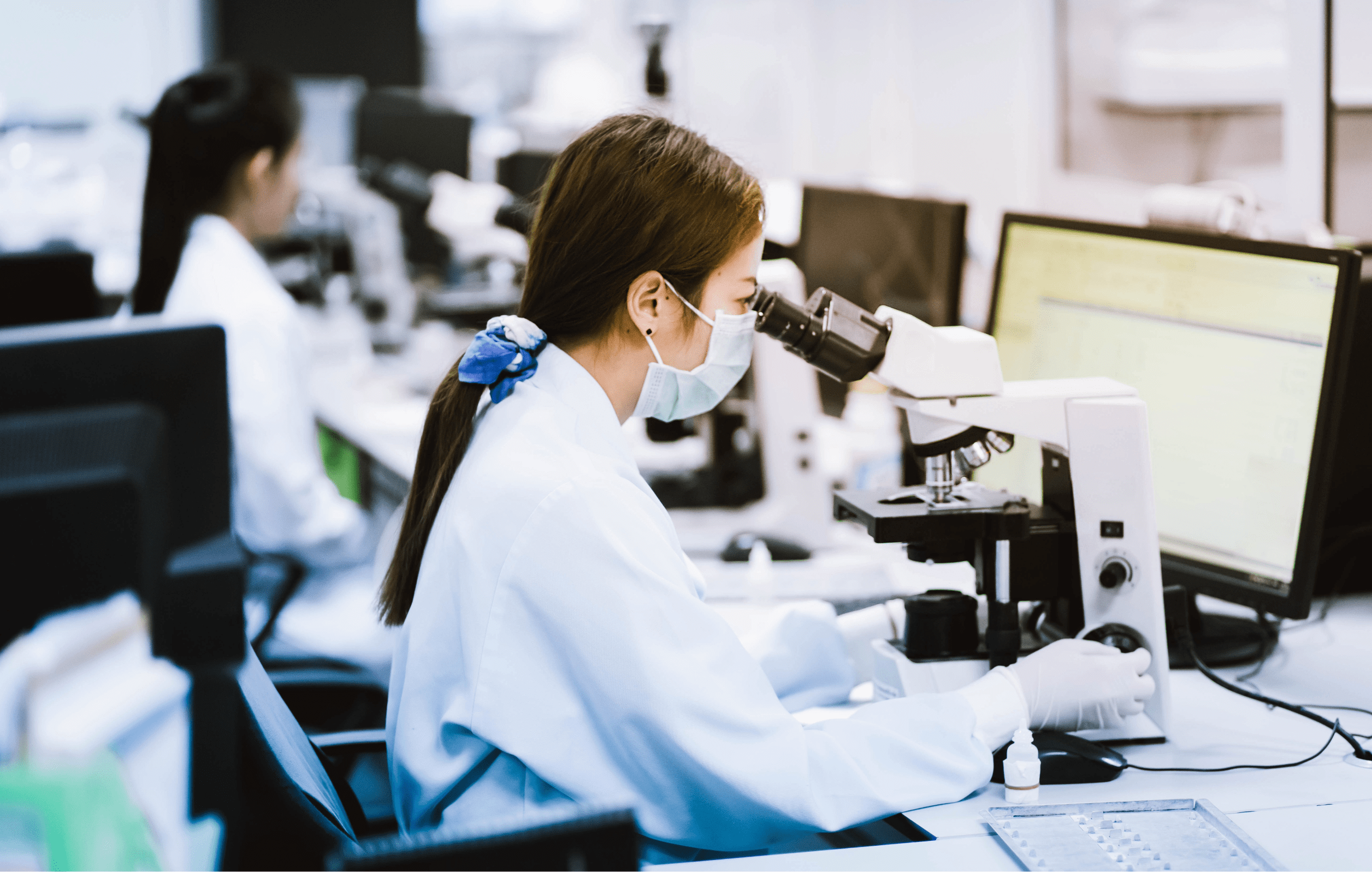 Female lab worker looking through a microscope